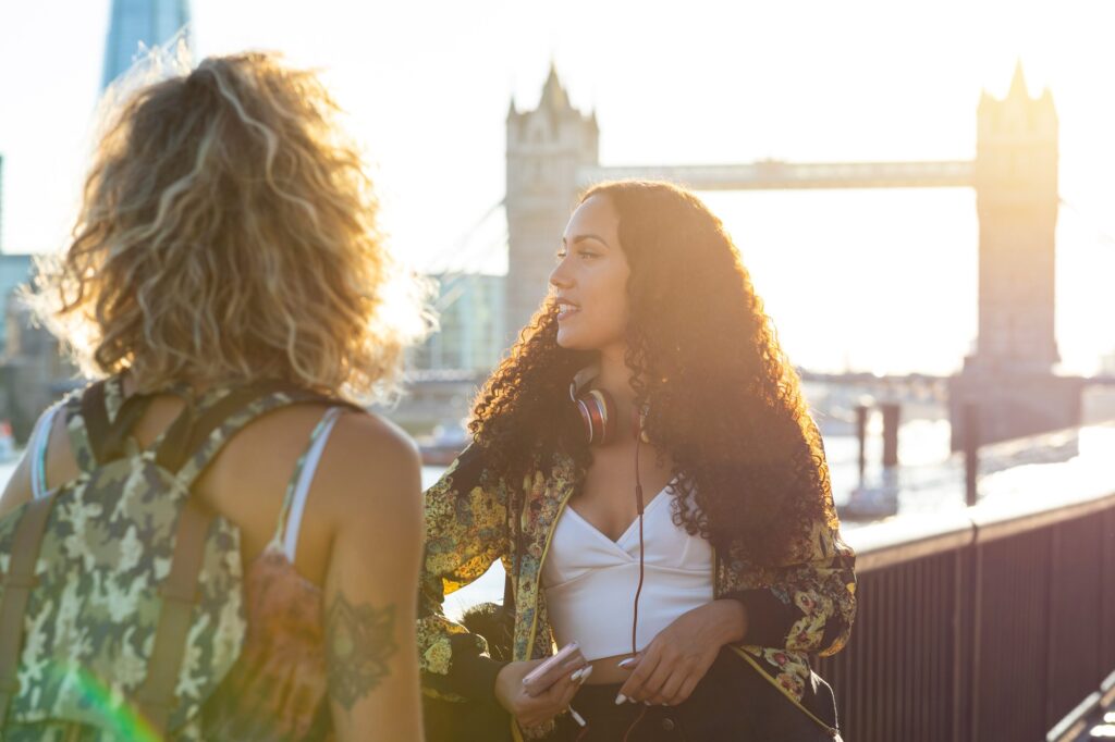 UK, London, two friends together in the city with Tower Bridge in background at sunset | SUPERPOBYT Travel