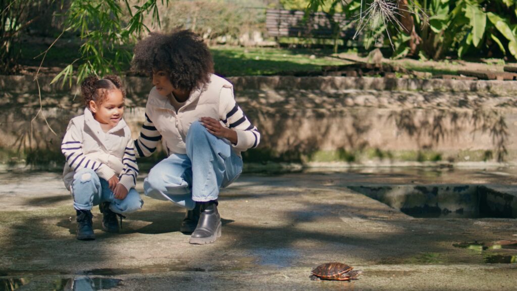 Woman girl watching reptile in sunny park. African family enjoying wildlife | SUPERPOBYT Travel